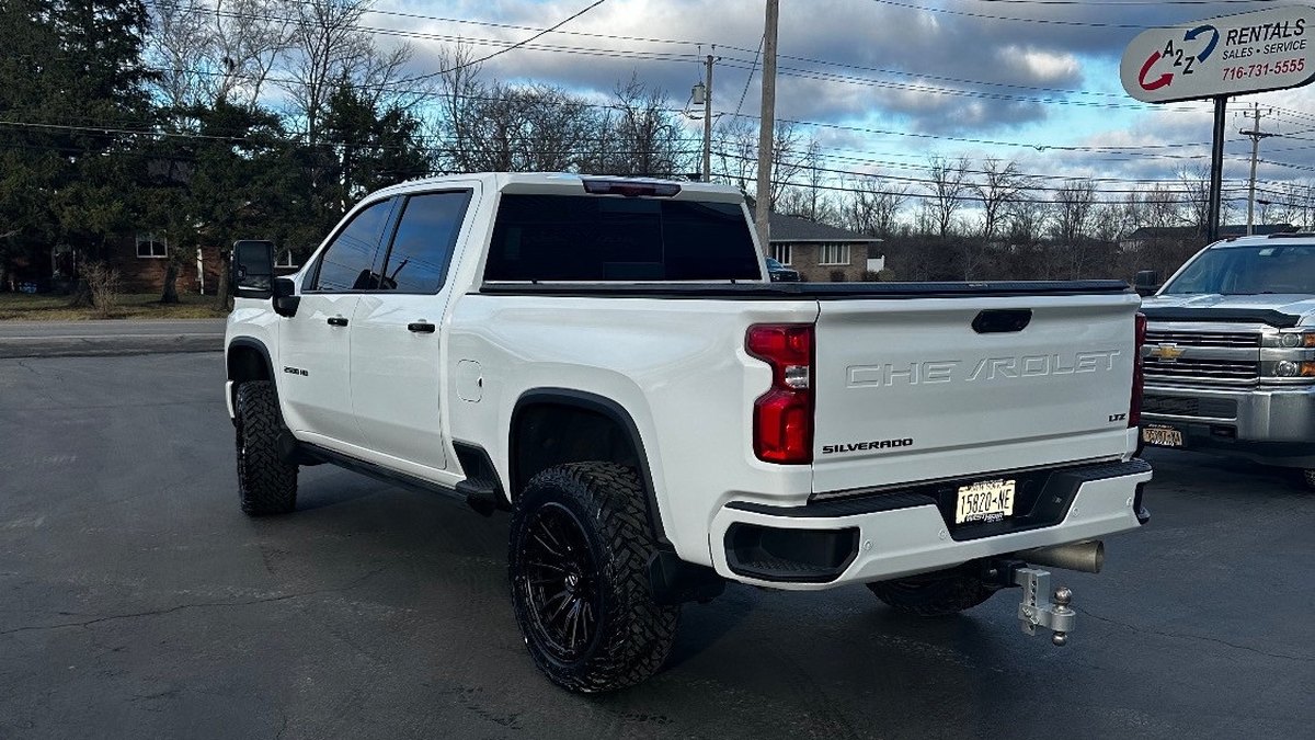A lifted white Chevy Silverado with a gooseneck ball in the bed
